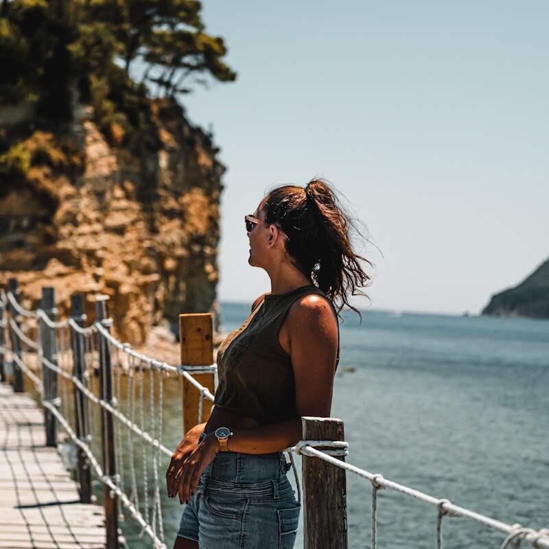 woman in blue denim shorts standing on bridge during daytime