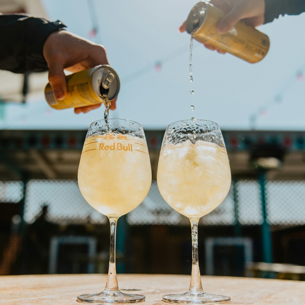 person pouring yellow liquid on clear drinking glass